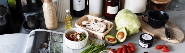 Various colorful healthy food and vegetables locating on countertop next to many different utensils and white kettle during cooking in stylish kitchen